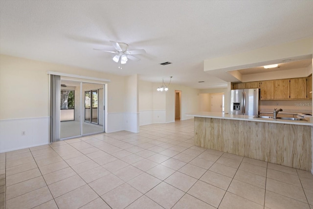 kitchen with light tile patterned floors, light countertops, stainless steel refrigerator with ice dispenser, wainscoting, and open floor plan