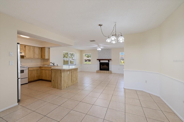 kitchen featuring light tile patterned floors, a ceiling fan, a peninsula, light countertops, and open floor plan