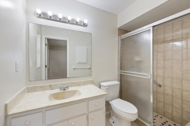 full bathroom with vanity, toilet, a shower stall, and a textured ceiling