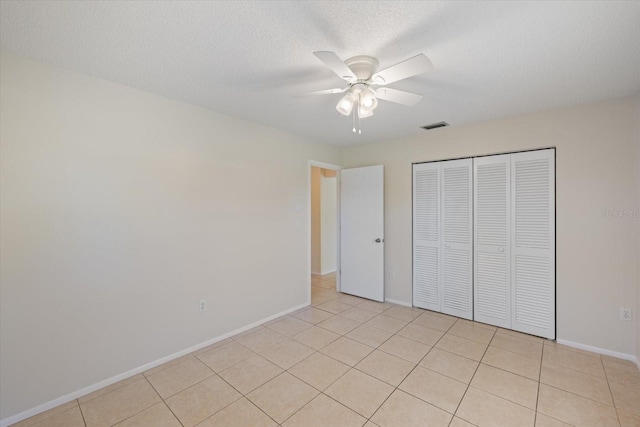 unfurnished bedroom with visible vents, baseboards, light tile patterned floors, a closet, and a textured ceiling