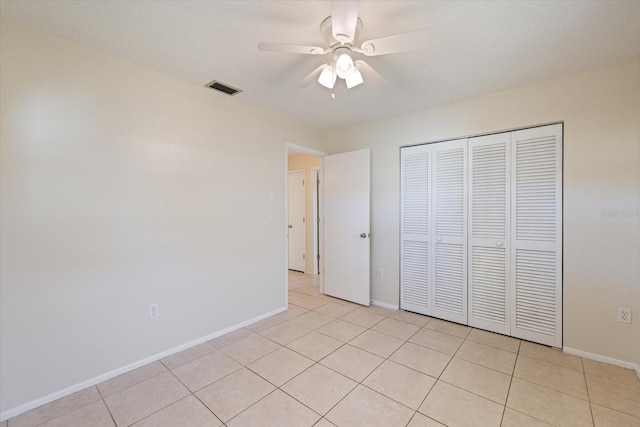 unfurnished bedroom with light tile patterned floors, baseboards, visible vents, ceiling fan, and a closet