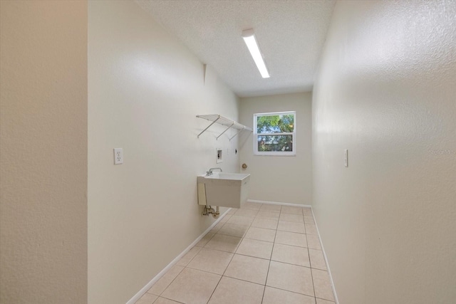 laundry area with baseboards, washer hookup, laundry area, light tile patterned flooring, and a textured ceiling