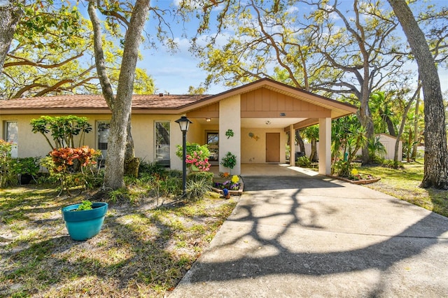 view of front of house with stucco siding, a carport, and driveway