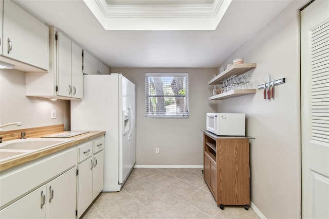 kitchen with a sink, baseboards, white appliances, and a tray ceiling