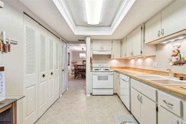 kitchen featuring a sink, under cabinet range hood, white appliances, light countertops, and a raised ceiling