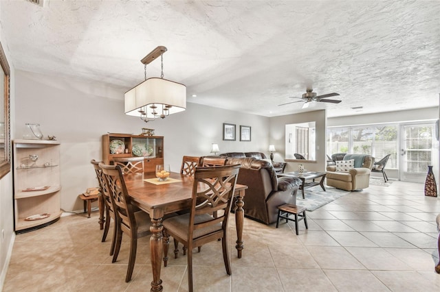 dining area featuring light tile patterned floors, a textured ceiling, and ceiling fan with notable chandelier