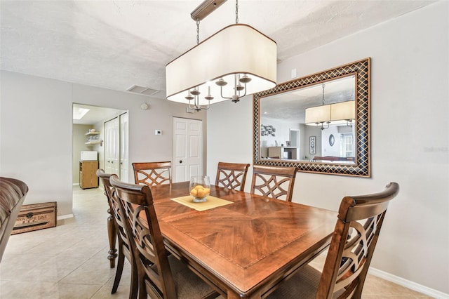 dining space featuring light tile patterned flooring, baseboards, visible vents, and a textured ceiling