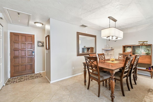 dining room featuring light tile patterned floors, visible vents, a textured ceiling, and attic access