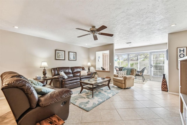 living area with light tile patterned flooring, a ceiling fan, baseboards, and a textured ceiling