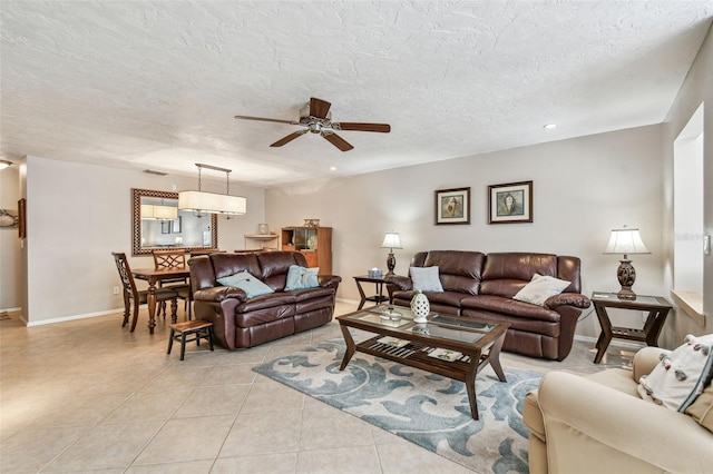 living area featuring light tile patterned floors, baseboards, a textured ceiling, and a ceiling fan