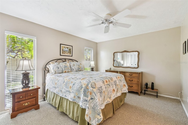 bedroom featuring baseboards, light colored carpet, and ceiling fan