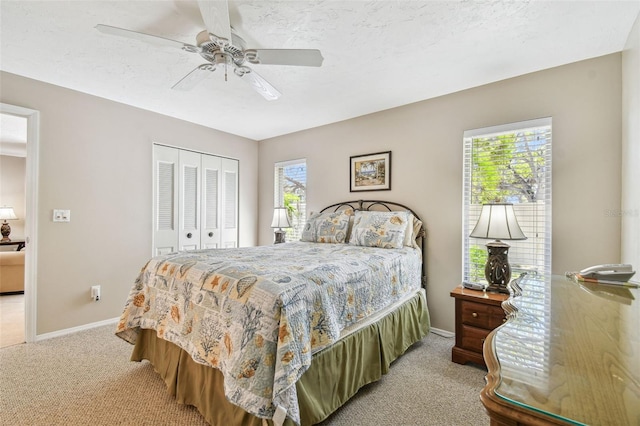 bedroom featuring multiple windows, baseboards, a closet, and light carpet