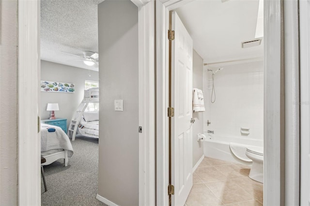 bathroom with tile patterned floors, a ceiling fan, ensuite bathroom, a textured ceiling, and shower / tub combination