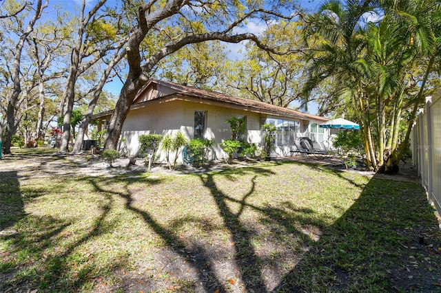 exterior space with a yard, fence, and stucco siding