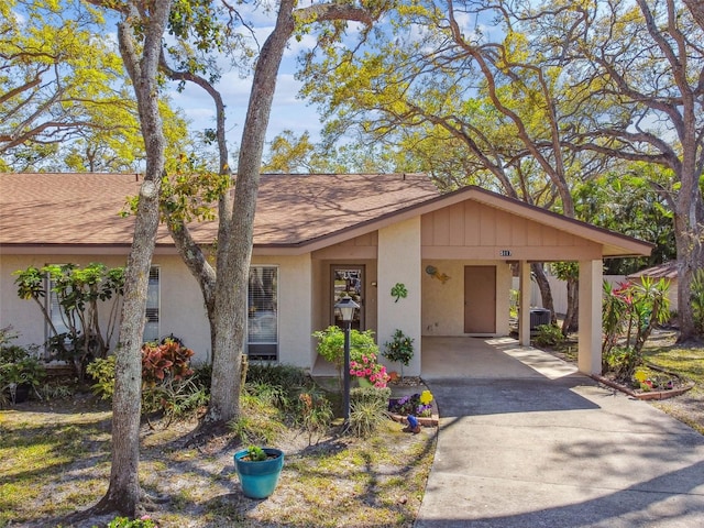 view of front of home with a shingled roof, a carport, driveway, and stucco siding