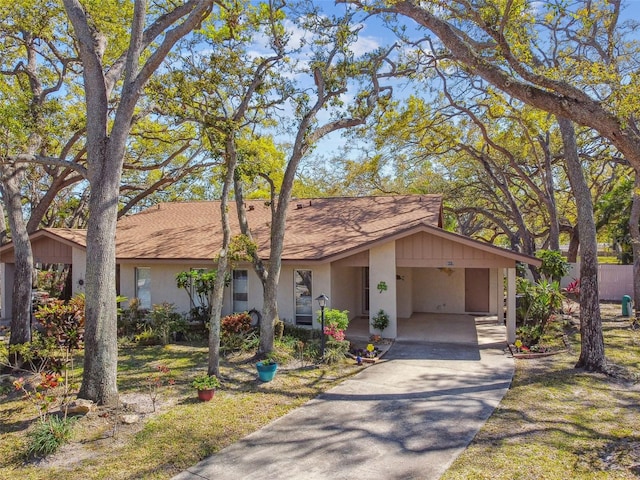 view of front of house featuring stucco siding, a carport, concrete driveway, and a shingled roof