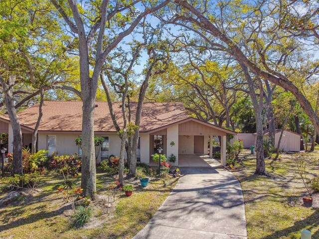 view of front facade featuring an outbuilding, stucco siding, concrete driveway, a carport, and a storage shed