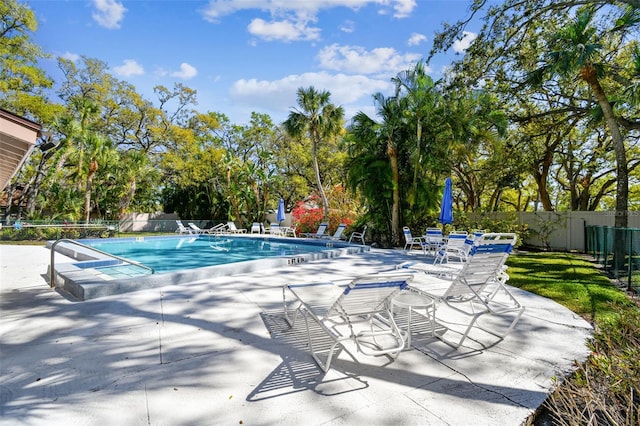 community pool with a patio area and fence