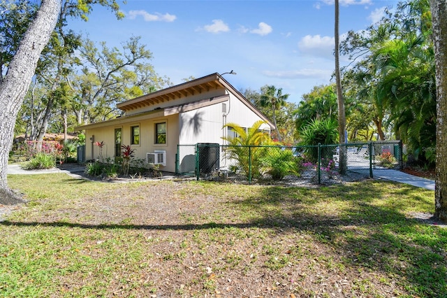 back of property featuring fence, an AC wall unit, a lawn, and a gate