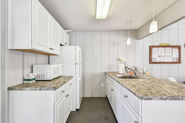 kitchen with white appliances, white cabinets, decorative light fixtures, and a sink