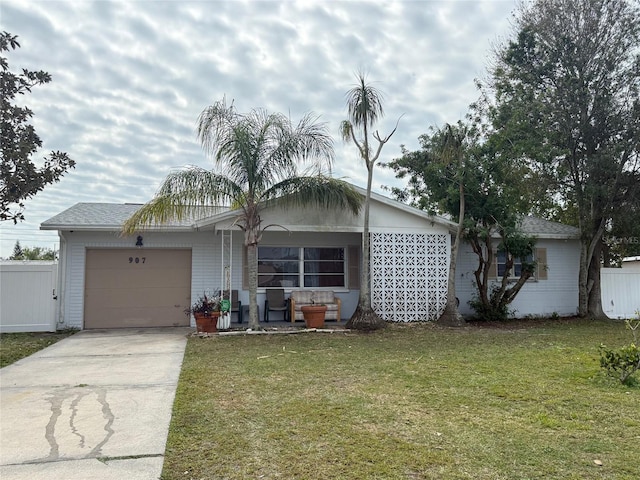 ranch-style house featuring an attached garage, concrete driveway, a front lawn, and fence