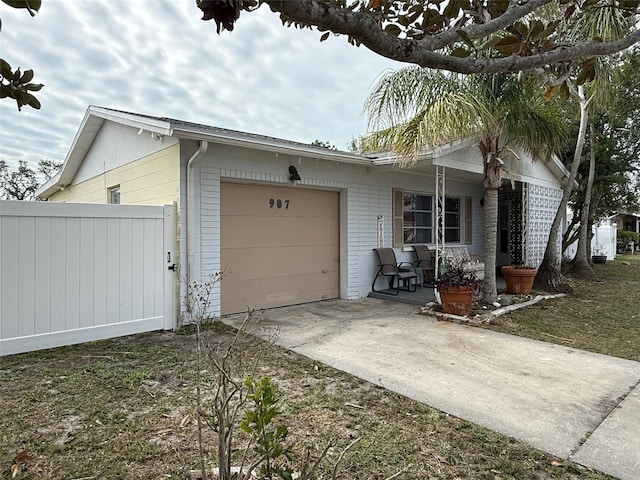 view of front of property with brick siding, fence, a porch, a garage, and driveway