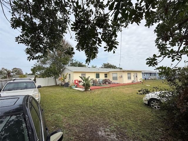 view of front facade with a wooden deck, cooling unit, a front lawn, and fence