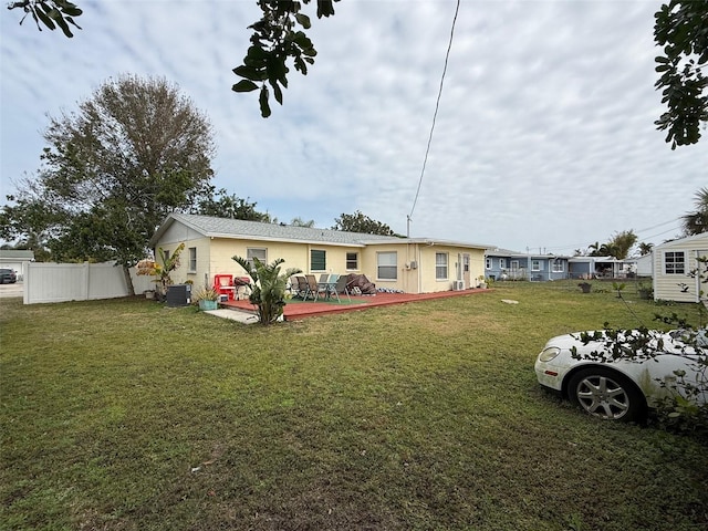 rear view of house featuring central air condition unit, a lawn, a deck, and fence