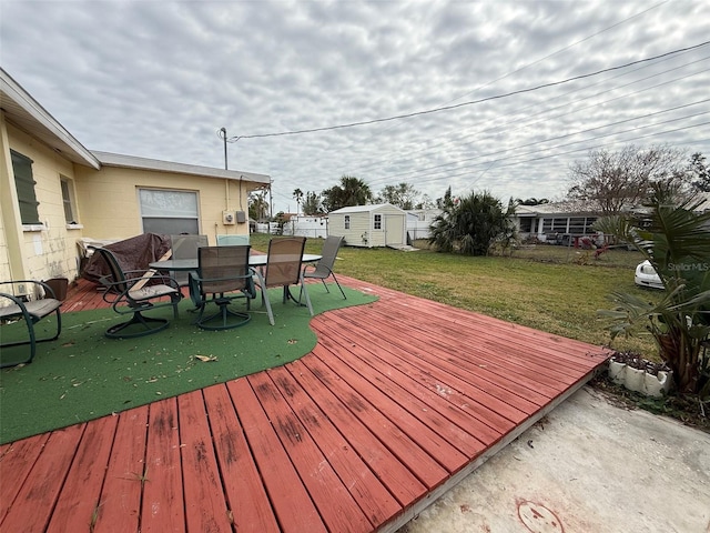 deck with outdoor dining area, a yard, and an outdoor structure