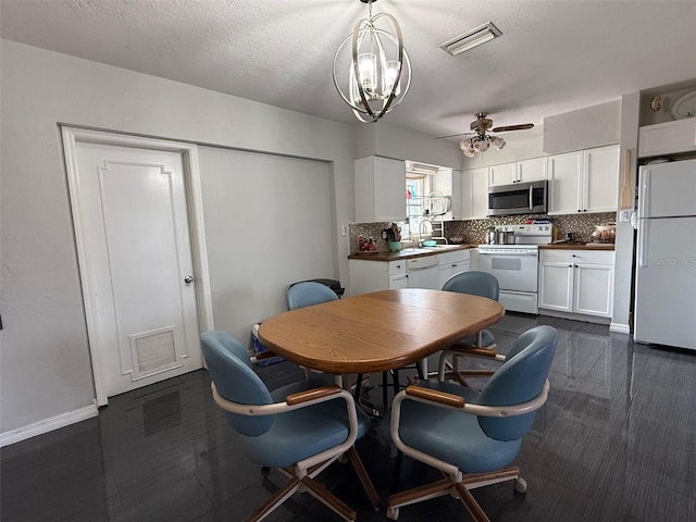 dining room featuring visible vents, baseboards, a textured ceiling, and ceiling fan with notable chandelier