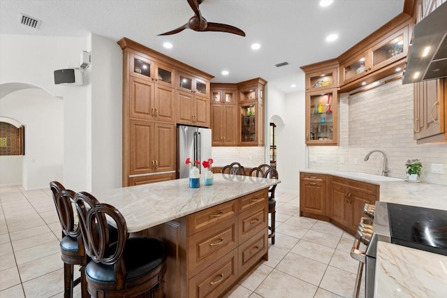 kitchen with visible vents, a sink, a kitchen breakfast bar, stainless steel appliances, and arched walkways