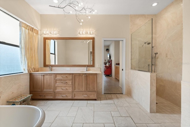 bathroom with double vanity, a soaking tub, a sink, a walk in shower, and a notable chandelier