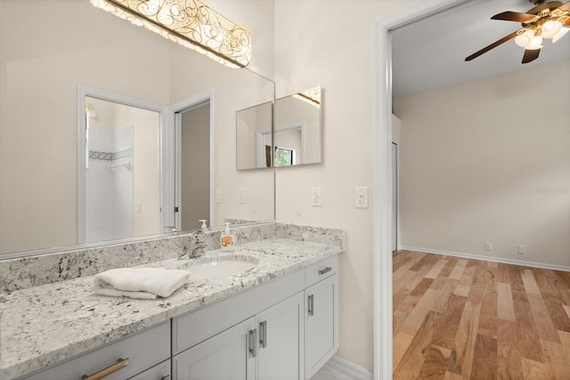 bathroom with baseboards, a ceiling fan, wood finished floors, and vanity