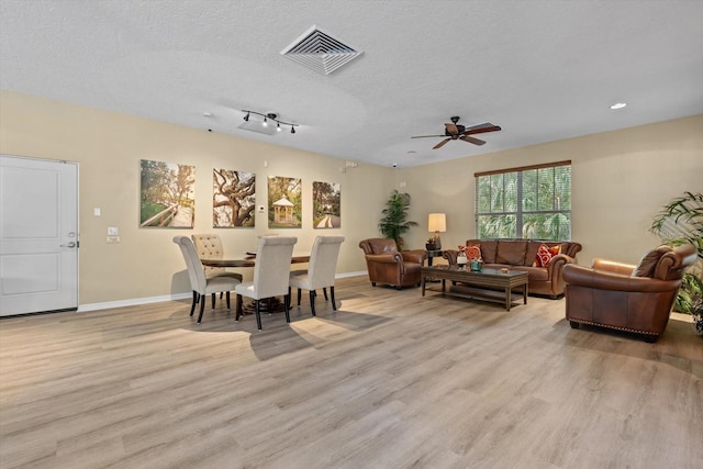 dining room with visible vents, light wood-style flooring, a textured ceiling, and baseboards