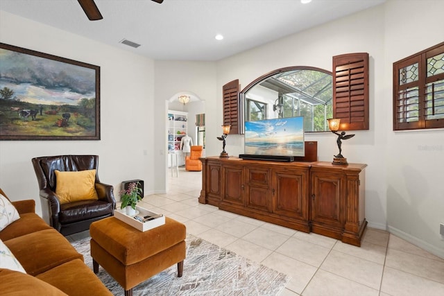 living room featuring visible vents, ceiling fan, baseboards, light tile patterned floors, and arched walkways