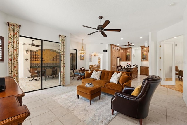 living area with light tile patterned floors, recessed lighting, and ceiling fan with notable chandelier