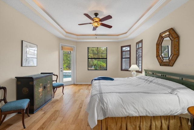 bedroom with access to exterior, baseboards, ornamental molding, light wood-style floors, and a raised ceiling