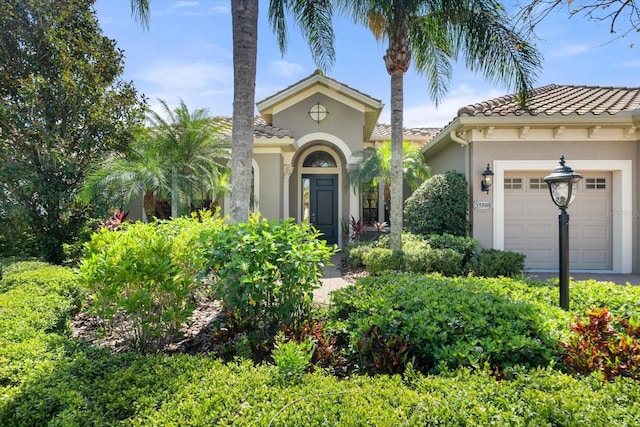 mediterranean / spanish house featuring stucco siding, a tiled roof, and a garage