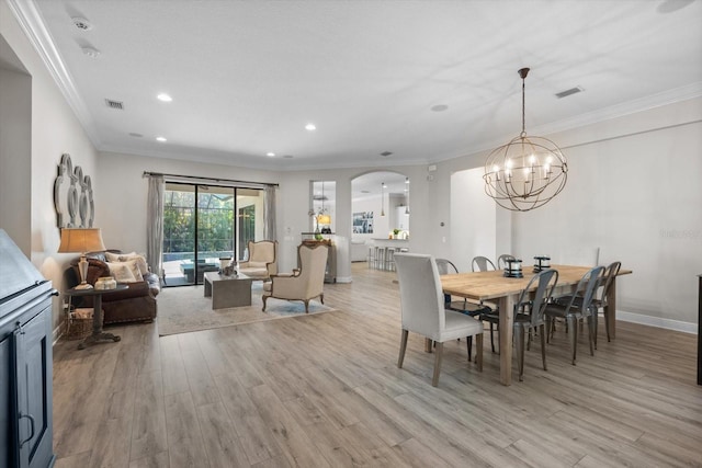 dining space with light wood-style flooring, visible vents, arched walkways, and ornamental molding