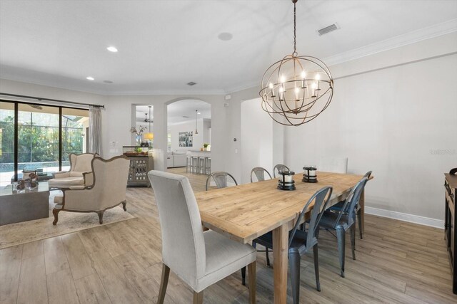 dining space featuring visible vents, arched walkways, crown molding, and light wood finished floors