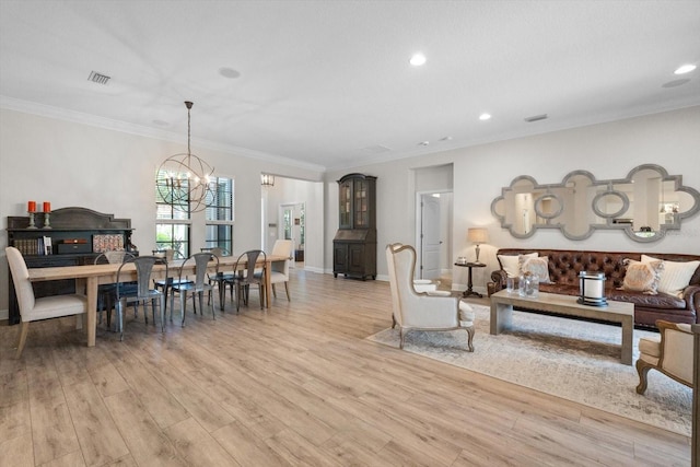 living room with light wood finished floors, visible vents, baseboards, a chandelier, and ornamental molding