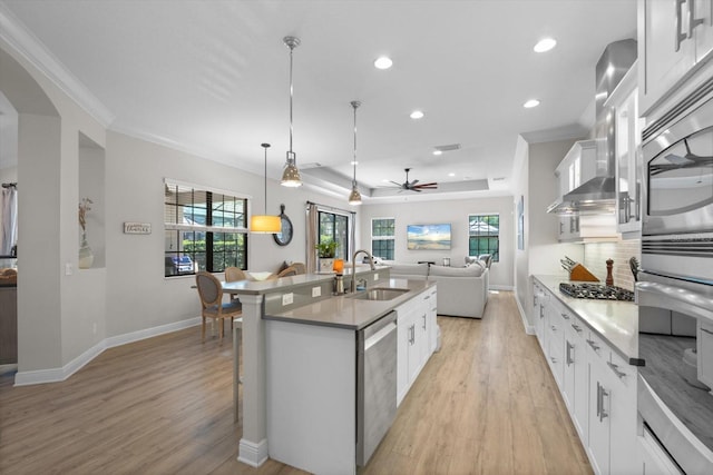 kitchen featuring light wood-type flooring, a kitchen island with sink, open floor plan, appliances with stainless steel finishes, and decorative backsplash