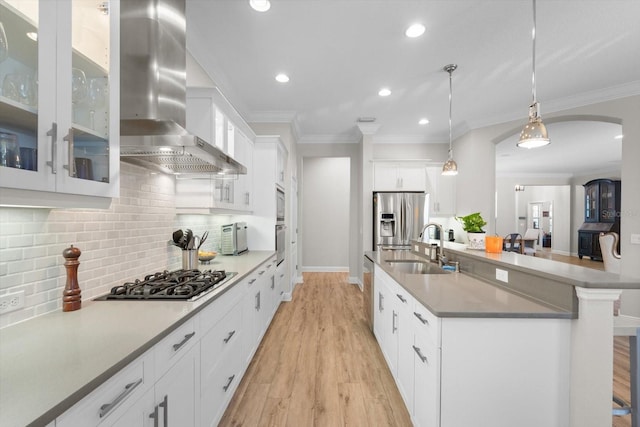 kitchen featuring a sink, stainless steel appliances, crown molding, and wall chimney range hood