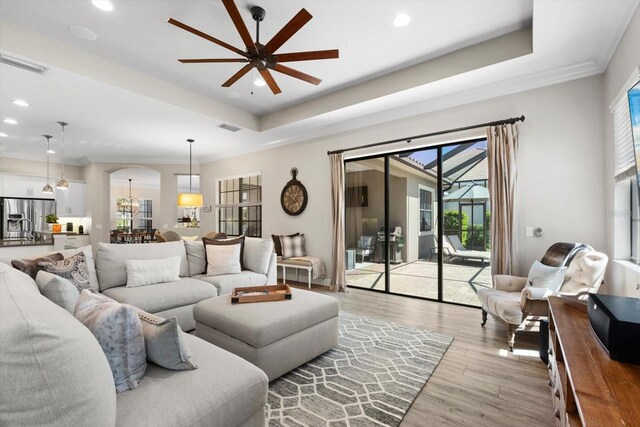 living area with visible vents, light wood-type flooring, and a raised ceiling