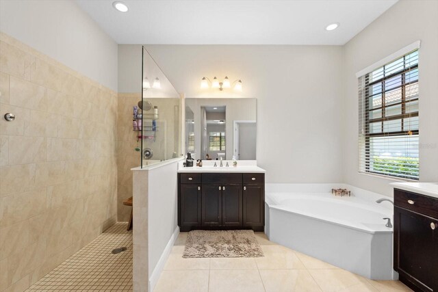 full bath featuring tile patterned flooring, a walk in shower, vanity, and a garden tub