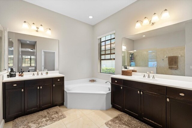 bathroom with a sink, a garden tub, two vanities, and tile patterned flooring