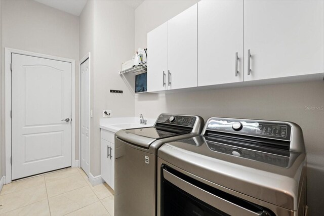 laundry area featuring a sink, light tile patterned floors, cabinet space, and washing machine and clothes dryer