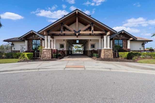 view of front of house featuring stucco siding, stone siding, and driveway