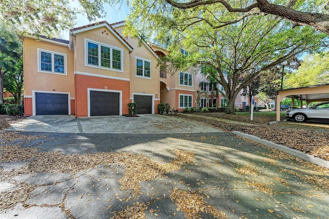 view of property with a garage, driveway, stucco siding, and a tiled roof