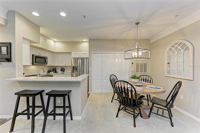 kitchen featuring visible vents, a chandelier, a peninsula, stainless steel appliances, and a sink